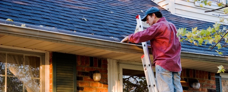 Man Cleaning Gutters on Ladder