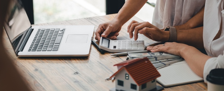 Couple hand use calculating interest, taxes and profits to invest in real estate and home buying